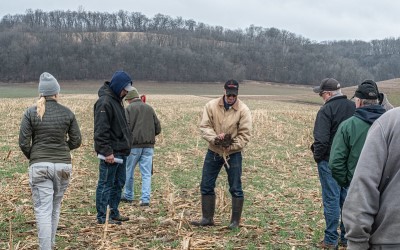 Farmer standing in field with crowd around, looking at cover crops