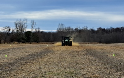 tractor driving through field, spreading a lime